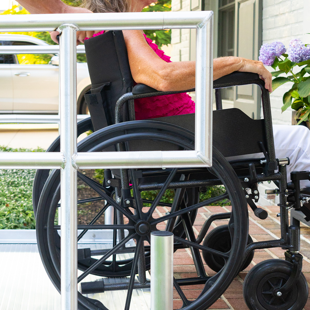 Close-up of a Rampit USA aluminum handrail with square ends alongside a wheelchair on the residential ramp.