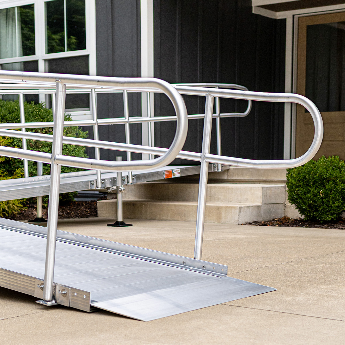 Rampit USA aluminum ramp with self-adjusting bevel at the entrance, providing a smooth transition alongside ANSI loops and handrail posts.